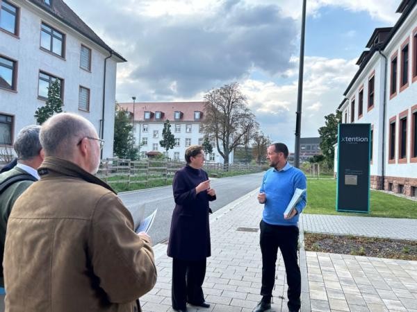 Ein Mann steht vor einem Gebäude und erklärt einer Frau die weiteren Baumaßnahmen.