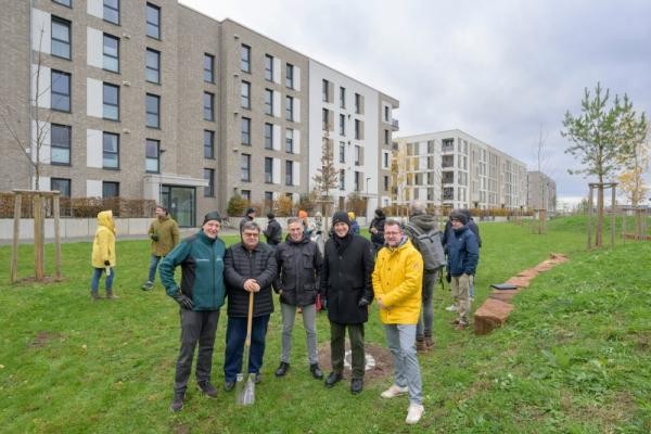 Die Bürgermeister Raoul Schmidt-Lamontain und Jürgen Odszuck übergaben am Freitag die neue Grünfläche an die Bevölkerung (v.l.n.r.: Dr. Ernst Baader, Holger Werner, Gerald Dietz, Jürgen Odszuck und Raoul Schmidt-Lamontain) (Foto: Rothe) Fünf Männer stehen auf einer grünen Wiese vor modernen Wohnhäusern.