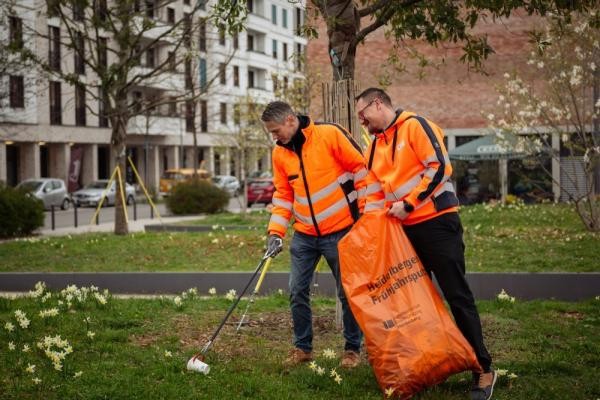 Beim Frühjahrsputz wurde in diesem Jahr mit mehr als 3.800 Teilnehmenden ein neuer Rekord erreicht. Auch Andreas Bieber, Leiter der Stadtreinigung (links), sammelte Abfall in der Bahnstadt ein. (Foto: Stadt Heidelberg) Zwei Männer sammeln mit Greifzangen Müll vom Boden auf und werfen ihn in einen orangenen Müllsack.