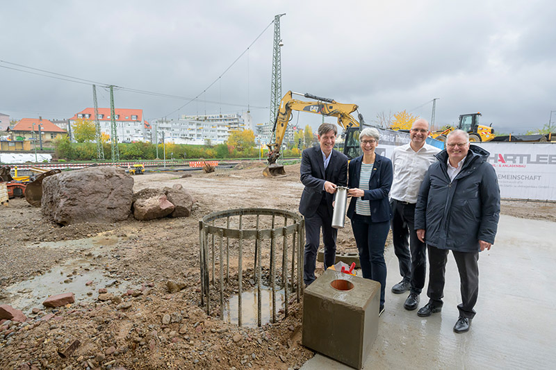 Grundsteinlegung mit Erstem Bürgermeister Odszuck (Foto: Rothe) Vier Personen stehen auf einer Baustelle.